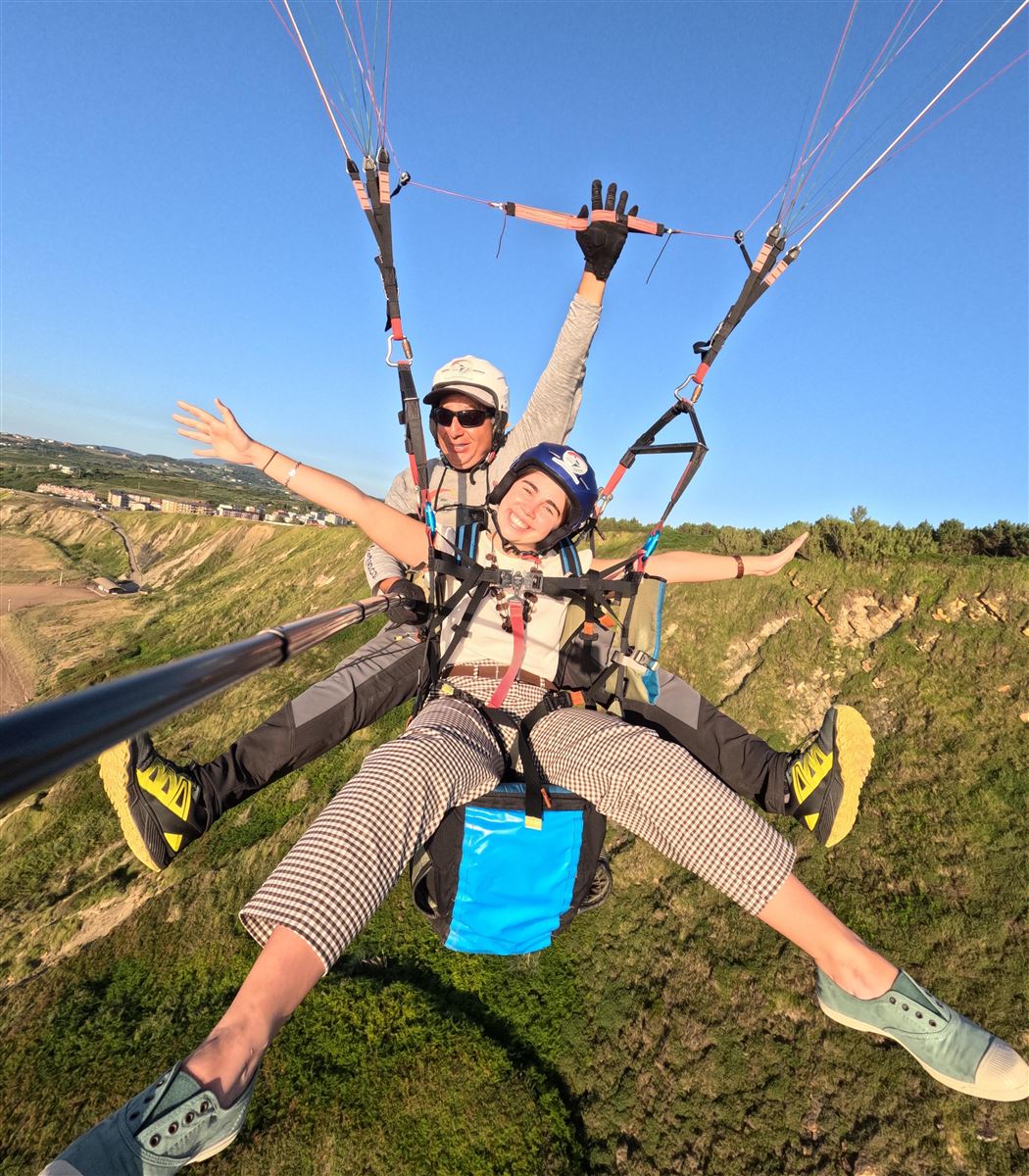 Douglas y pasajera sonriendo durante el vuelo en parapente